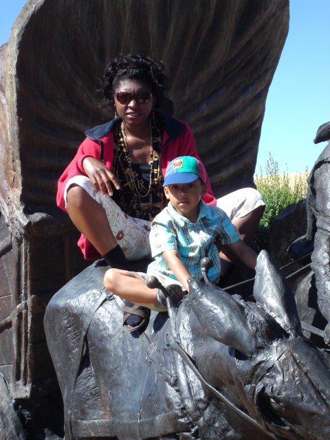 Joanitha and Joachim on a bronze covered wagon, Santa Fe, New Mexico, 2009